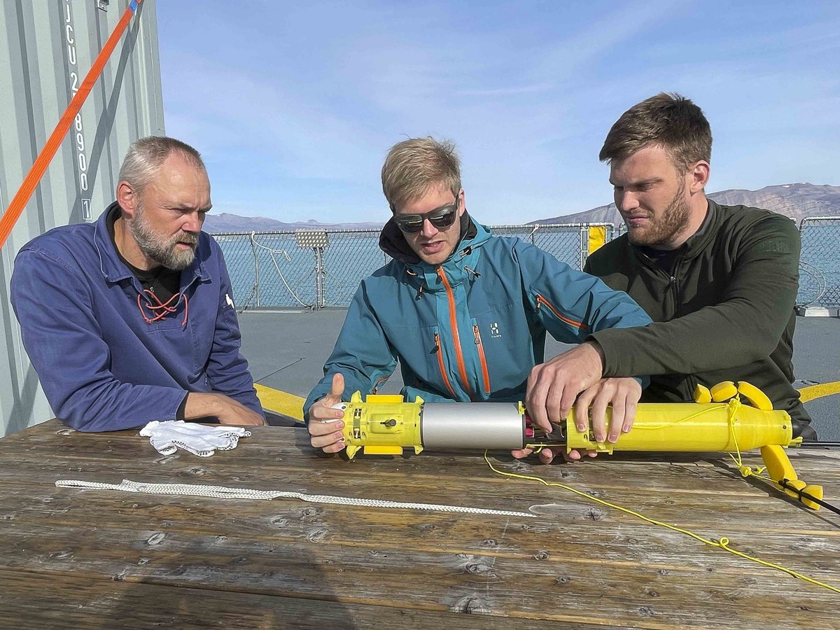 Before the drop, Professor Søren Rysgaard and the two young engineers Ebbe Poulsen and Mathias Eggertsen check the probe designed to measure temperature, pressure and salinity in the icy fjords in Northeast Greenland. Photo: Peter Bondo Christensen.