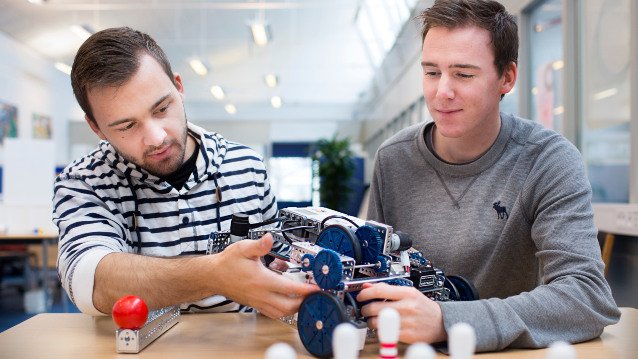 Billede af to personer der kigger på en robot. 
